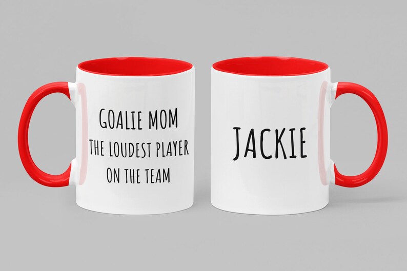 May include: Two white ceramic mugs with red handles and red interior rims. One mug says "Goalie Mom The Loudest Player On The Team" and the other mug says "Jackie".