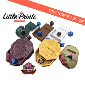 May include: A set of six colourful, 3D printed dice towers, each with a different design and colour. The towers are made to hold dice for tabletop games. The towers are labelled "Tiny Towers Fates End TT102".