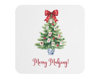 May include: A square white coaster featuring a watercolour illustration of a Christmas tree adorned with Mahjong tiles. The tree is topped with a red bow and is set in a blue and white vase. The words "Merry Mahjong!" are written in red.