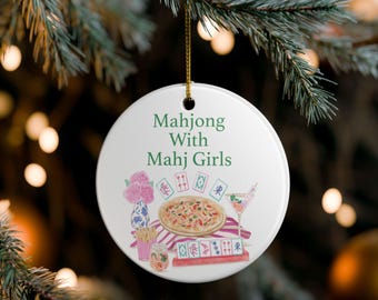 Könnte beinhalten: Ein weißer, runder Weihnachtsschmuck mit dem grünen Text "Mahjong With Mahj Girls". Der Schmuck zeigt Aquarellillustrationen von Mahjong-Steinen, einer Pizza, einem Cocktail und Blumen. Ein goldener Faden ist zum Aufhängen befestigt.