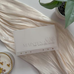 Puede incluir: Un organizador de mantenimiento de automóviles blanco translúcido con las palabras "MAINTENANCE CAR car maintenance" impresas en una escritura gris claro. El organizador tiene varios agujeros perforados a lo largo del borde inferior.