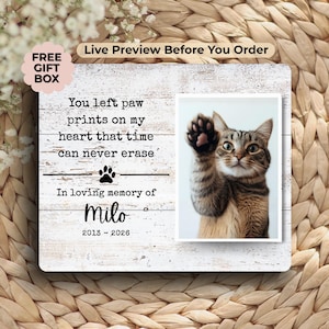 May include: A wooden pet memorial frame with a photo of a cat raising its paw. The frame has the text "You left paw prints on my heart that time can never erase" and "In loving memory of Milo 2013-2026".