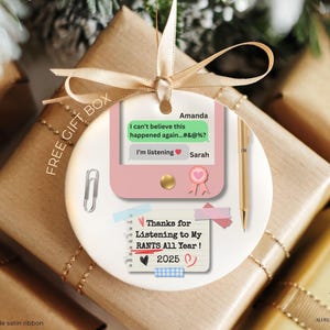 Könnte beinhalten: Runder, weißer Keramikschmuck mit einem rosa Telefongrafik und dem Text "Thanks for Listening to My RANTS All Year! 2025." Enthält ein goldenes Band zum Aufhängen. Eine Büroklammer und ein Stift sind ebenfalls abgebildet.