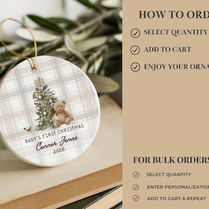May include: A round white ceramic ornament featuring a beige and white plaid pattern, a decorated Christmas tree, and a brown teddy bear. The text reads BABY'S FIRST CHRISTMAS, Connor Jonas, and 2026. It includes a gold hanging string.