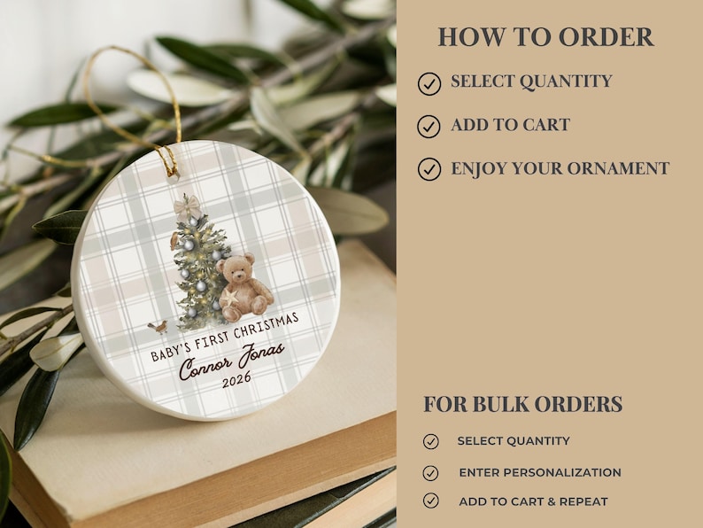 May include: A round white ceramic ornament featuring a beige and white plaid pattern, a decorated Christmas tree, and a brown teddy bear. The text reads BABY'S FIRST CHRISTMAS, Connor Jonas, and 2026. It includes a gold hanging string.