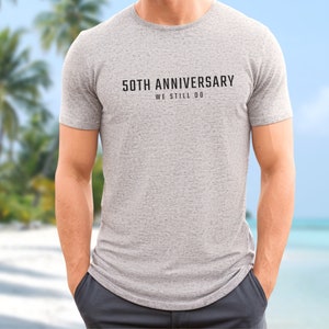 May include: A gray t-shirt with the text "50th Anniversary We Still Do" printed on the front.