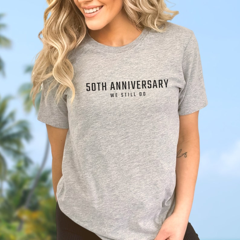 May include: A gray t-shirt with the text "50th Anniversary We Still Do" printed in black.