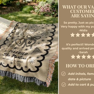 May include: A beige personalized wedding blanket with black decorative elements, including hearts, stars, and a cake. The blanket features the text "MARRIED" and the date "NOVEMBER 11, 2025". It has a scalloped edge and fringe.