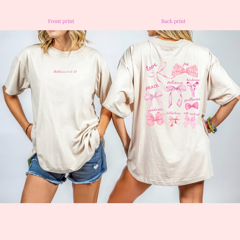 May include: Beige t-shirt with pink text and bow designs. The front of the shirt has the text "Galatians 5:22-23". The back features the words "love, peace, joy, patience, kindness, goodness, gentleness, faithfulness, self control" with bow illustrations.