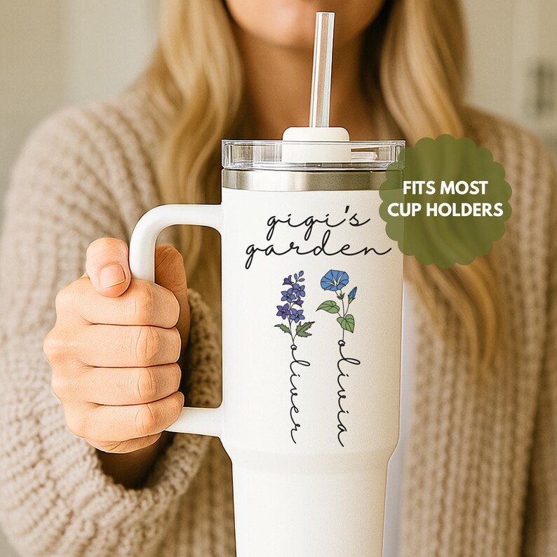 May include: White travel mug with a black lid and a straw. The mug has a floral design with the text "gigi's garden" and the names "oliver" and "olivia" written vertically.