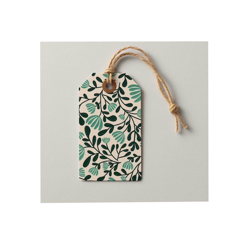 Pode incluir: Uma etiqueta de presente retangular de papel com fundo creme e um padr&atilde;o repetitivo de folhas verde-escuras e formas florais em tom azul-petr&oacute;leo claro. A etiqueta possui um ilh&oacute; refor&ccedil;ado castanho e um cordel bege no orif&iacute;cio superior.