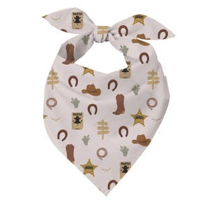 May include: A white triangular bandana featuring a repeating pattern of brown cowboy boots, brown cowboy hats, gold sheriff stars, brown horseshoes, green cacti, tan directional signs, lassos, and tan wanted posters with the text WANTED.
