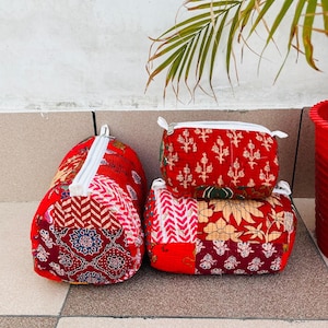 May include: Four red and white patterned fabric zippered pouches. The pouches are made of quilted fabric with different floral and geometric designs.