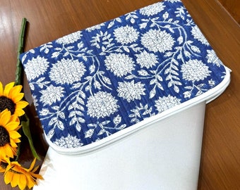 May include: A blue and white floral laptop sleeve with a zipper closure. The sleeve is made of a soft, quilted fabric and has a white lining.