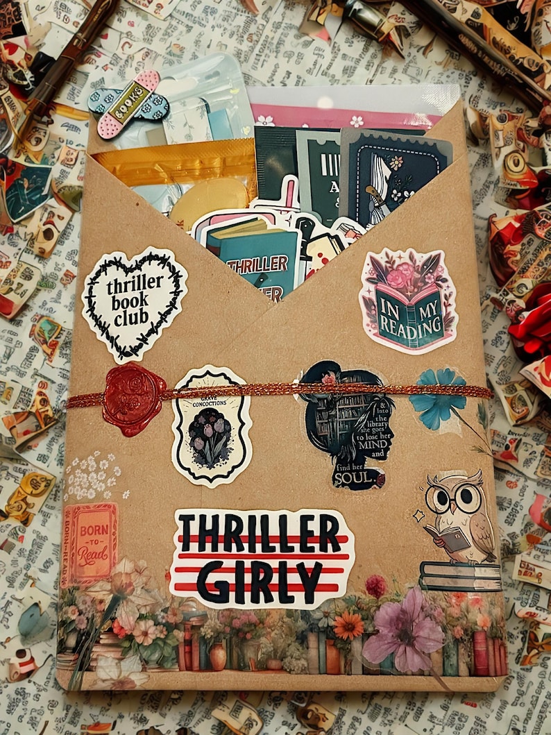 Pu&ograve; includere: Una busta di carta marrone riempita con vari adesivi e articoli di cancelleria. La parte anteriore presenta adesivi tra cui un cuore con il testo thriller book club, una silhouette con testo e una grande etichetta con scritto THRILLER GIRLY, sigillata con ceralacca rossa.