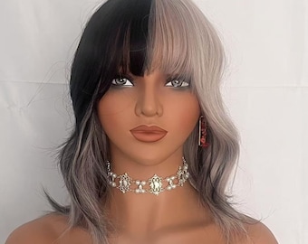 May include: A half black and half silver grey wig with bangs on a mannequin head. The wig has a wavy texture. The mannequin is wearing a silver choker necklace and red earrings. The text "BAG Wigs" is on a green label in the bottom centre of the image.