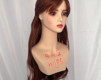 May include: A mannequin head displaying a long, auburn wig with a fringe and flowing layers. The mannequin has a neutral expression with red lipstick. The words "BAG wigs" are written in red marker on the neck.