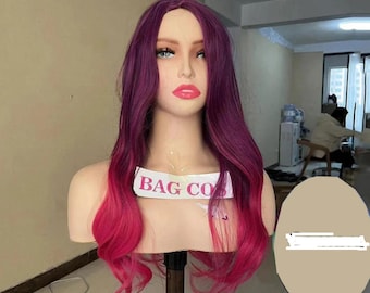 May include: A mannequin head showcasing a long, wavy wig with a colour gradient. The wig fades from a deep purple at the roots to a bright pink at the ends. The mannequin has realistic facial features and the text "BAG CO" is visible.