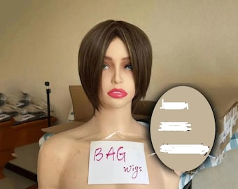 May include: A mannequin head displaying a short, brown wig with blonde streaks. The mannequin has red lips and is wearing makeup. A handwritten sign reads "BAG wigs".