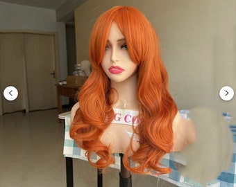May include: A long, wavy, orange wig with side-swept bangs. The wig is styled in loose curls and is worn on a mannequin head.