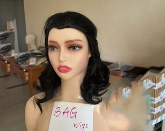 May include: A black wig with loose curls on a mannequin head. The wig is labelled "BAG wigs" on a white piece of paper.