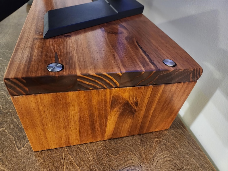 May include: A wooden box with a dark brown stain. The box has two silver screws on the top. The box is made of wood planks.