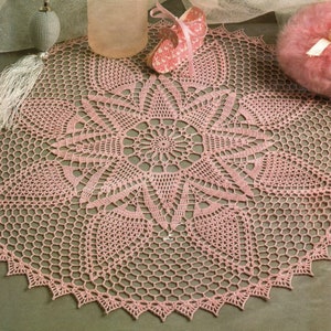 Puede incluir: Un encaje de ganchillo rosa con un delicado diseño floral. El encaje está colocado sobre una superficie texturizada con una botella de vidrio, un zapato rosa y una borla de polvo rosa.