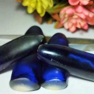 Könnte beinhalten: Vier blaue Glasflaschenverschlüsse mit einem dunkelblauen Wirbel im Inneren. Die Verschlüsse sind kugelförmig.