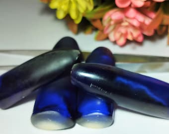 Puede incluir: Cuatro tapones de botella de vidrio azul con un remolino azul oscuro en el interior. Los tapones tienen forma de bala.