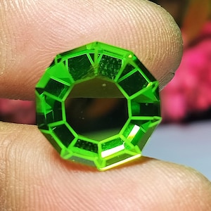 May include: A bright green faceted gemstone with a octagonal shape.