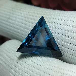 Könnte beinhalten: Ein dreieckiger blauer Edelstein mit Facettenschliff.