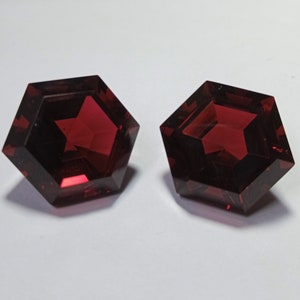 May include: Two red gemstone cabochons with a faceted hexagonal shape.