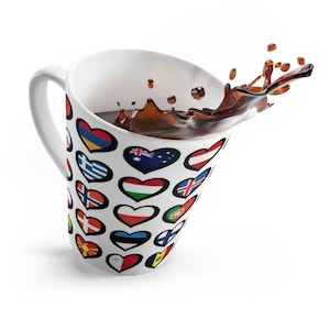 May include: A white ceramic mug with a design of hearts featuring flags from different countries. The mug is filled with coffee and the coffee is splashing out of the mug.