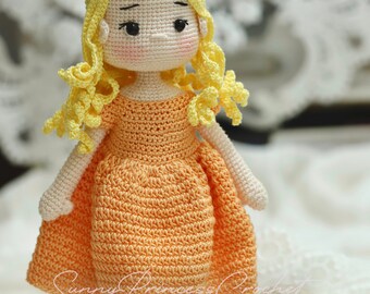 May include: A crocheted doll with yellow hair and an orange dress stands next to a white crocheted dog. The doll has black eyes and a sweet expression. The dog has black eyes and a red collar.