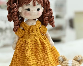 May include: A crocheted doll with brown hair in pigtails wearing a yellow dress and brown shoes. The doll is standing next to a crocheted dog with white and brown fur.
