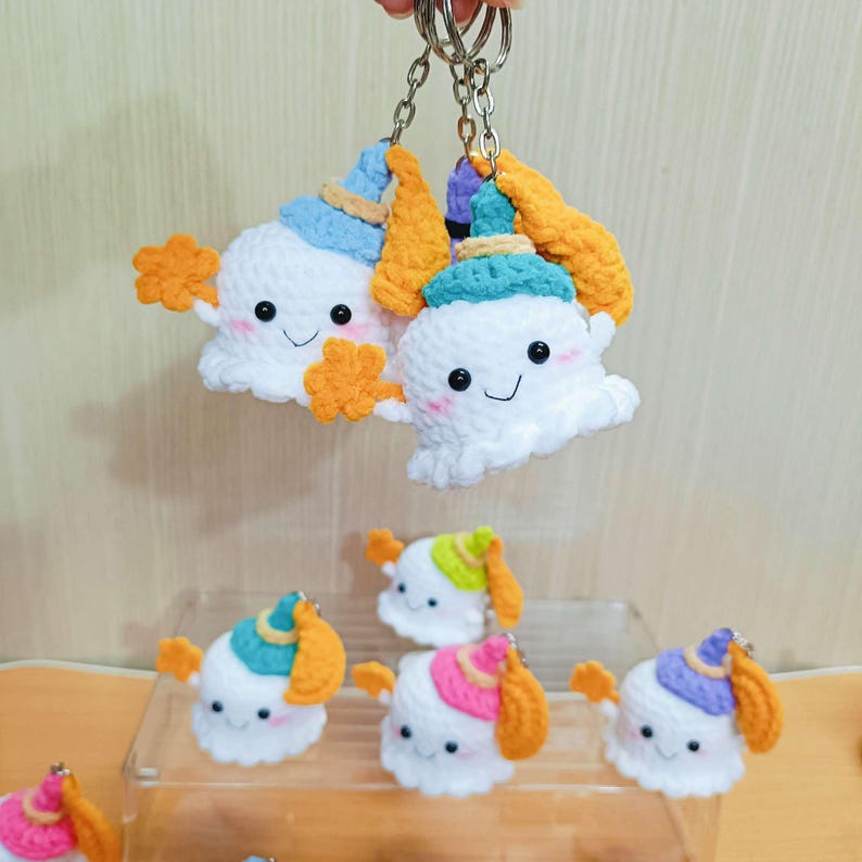 Puede incluir: Un conjunto de siete llaveros de fantasmas de crochet con sombreros de diferentes colores. Los fantasmas son blancos con ojos negros y una boca sonriente. Los sombreros son azules, verdes, rosas, morados y amarillos. Los llaveros est&aacute;n unidos a llaveros de plata.