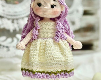 May include: A crocheted doll with long purple hair, wearing a white dress with a green and purple trim, and brown shoes.