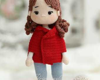 May include: A crocheted doll with brown hair wearing a red jacket, blue jeans, and red shoes. The doll is standing next to a white crocheted dog.