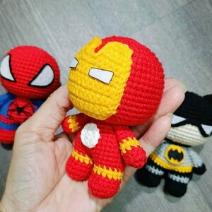 Puede incluir: Tres juguetes de superh&eacute;roes de crochet: un Spiderman rojo y azul, un Iron Man rojo y amarillo y un Batman negro y gris.