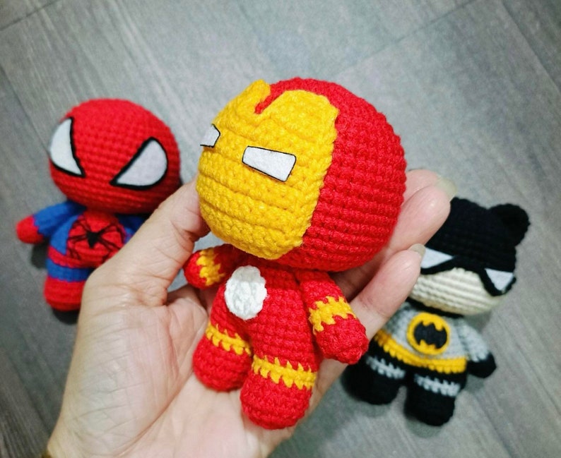 Puede incluir: Tres juguetes de superh&eacute;roes de crochet: un Spiderman rojo y azul, un Iron Man rojo y amarillo y un Batman negro y gris.