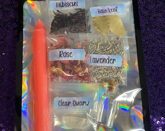 Può includere: Un sacchetto nero contenente vari oggetti per pratiche spirituali. Include una candela rosa, erbe essiccate etichettate "Ibisco", "Foglia di alloro", "Rosa" e "Lavanda", una piccola bottiglia di vetro e un cristallo di quarzo trasparente. Il sacchetto è etichettato "Amore".