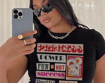 May include: Black t-shirt with a colorful graphic print that says "Princess", "Power", "Fun & Hot", "Success", "Pretty", and "It's What's Inside That Counts!" with a Capricorn zodiac symbol.