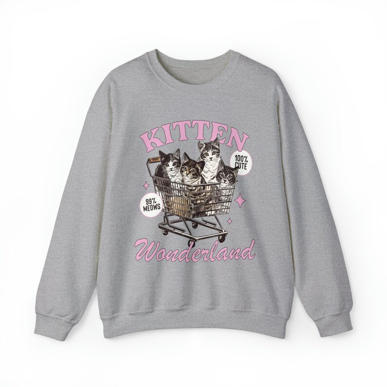 Puede incluir: Sudadera gris con un gr&aacute;fico rosa de cuatro gatitos en un carrito de compras. El gr&aacute;fico dice "Kitten Wonderland" e incluye el texto "99% Meows" y "100% Cute".