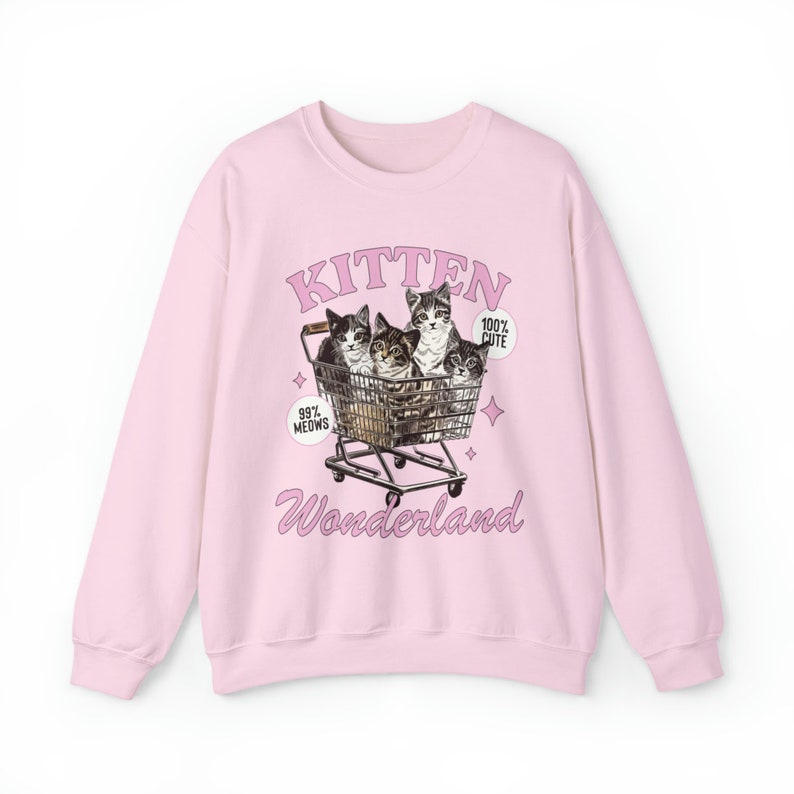 Puede incluir: Sudadera rosa con un gr&aacute;fico de cuatro gatitos en un carro de la compra. El texto "Kitten Wonderland" est&aacute; impreso debajo de la imagen. El texto "99% Meows" est&aacute; impreso en el lado izquierdo de la imagen y "100% Cute" est&aacute; impreso en el lado derecho de la imagen.