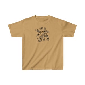 K&ouml;nnte beinhalten: Ein hellbraunes T-Shirt mit einer schwarzen Linienzeichnung von zwei Kolibris im Flug, die sich gegen&uuml;berstehen und sich mit ihren Schn&auml;beln ber&uuml;hren. Die Kolibris sind von Blumen und Bl&auml;ttern umgeben.