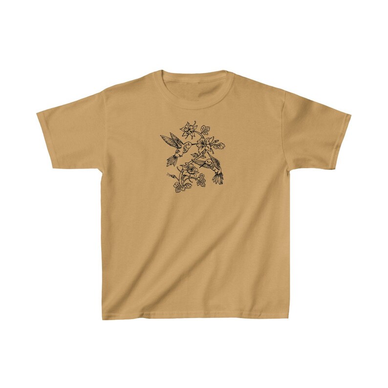 K&ouml;nnte beinhalten: Ein hellbraunes T-Shirt mit einer schwarzen Linienzeichnung von zwei Kolibris im Flug, die sich gegen&uuml;berstehen und sich mit ihren Schn&auml;beln ber&uuml;hren. Die Kolibris sind von Blumen und Bl&auml;ttern umgeben.