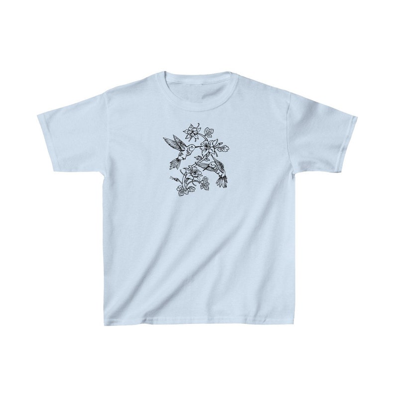 K&ouml;nnte beinhalten: Ein hellblaues T-Shirt mit einer schwarz-wei&szlig;en Illustration von zwei Kolibris im Flug, die sich gegen&uuml;berstehen und sich mit ihren Schn&auml;beln ber&uuml;hren. Die Kolibris sind von schwarzen und wei&szlig;en Blumen umgeben.