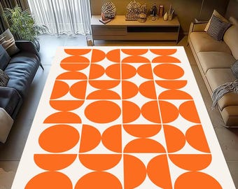 May include: A large rectangular rug with a geometric pattern. The rug features a repeating design of orange semi-circles and circles against a white background. The rug is placed in a living room setting, with furniture visible in the background.