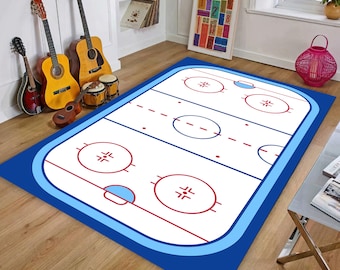 May include: A rectangular rug with a hockey rink design. The rug features a white surface with red circles and lines, replicating a hockey rink layout. The border is a bright blue. The rug is designed for indoor use, with dimensions suitable for a living space.