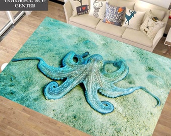 May include: A teal blue rug with a large octopus printed on it. The octopus has eight tentacles and is in a light blue color. The rug has a light green and white background.